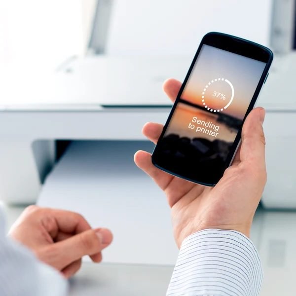 Hand holding a smartphone sending a print job to a printer