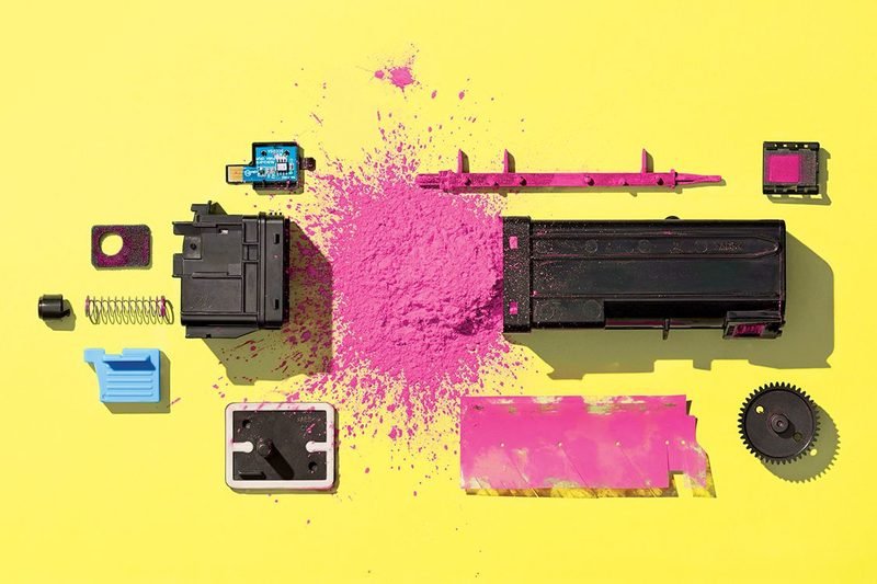 Laser toner cartridge taken apart showing magenta toner powder and internal parts