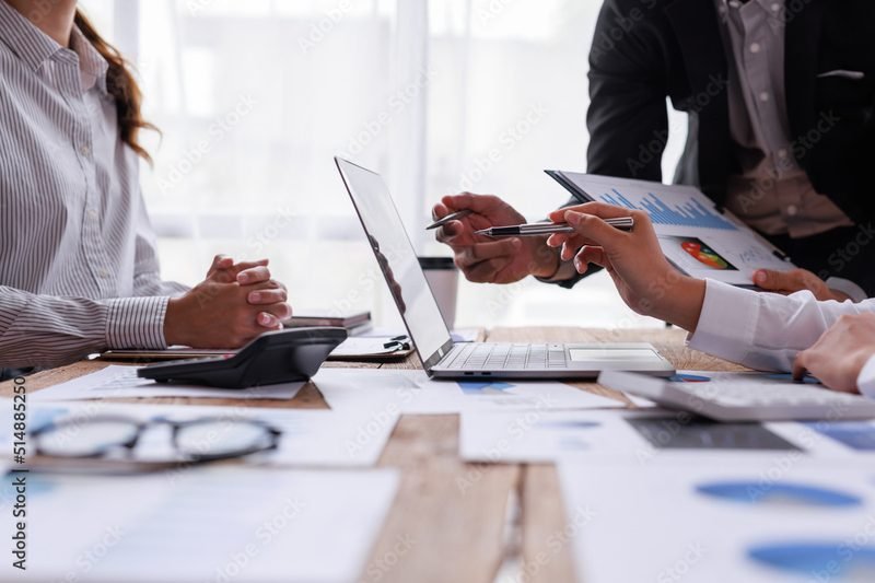 Business team reviewing printed reports around a table with laptops